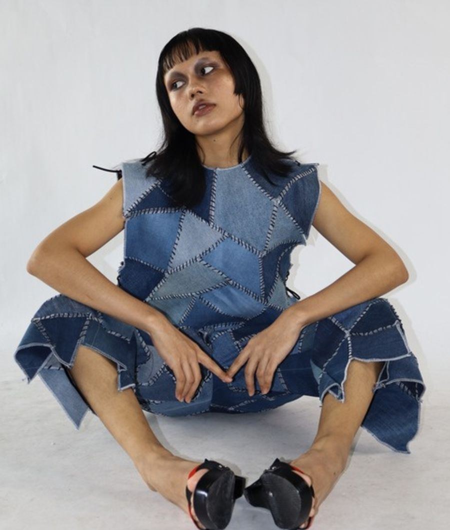 Seated in a patchwork denim two-piece